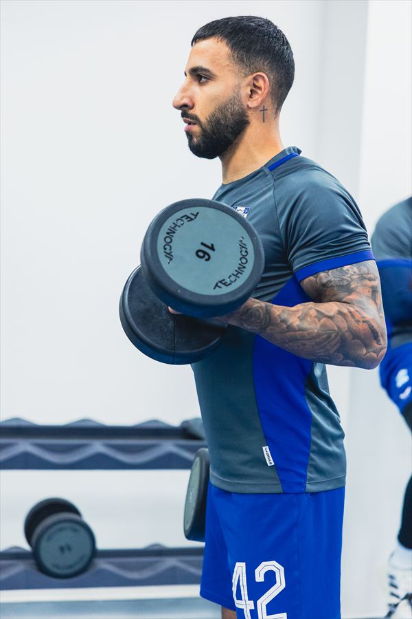 Renan Guedes faz exercício de força com halteres na academia.